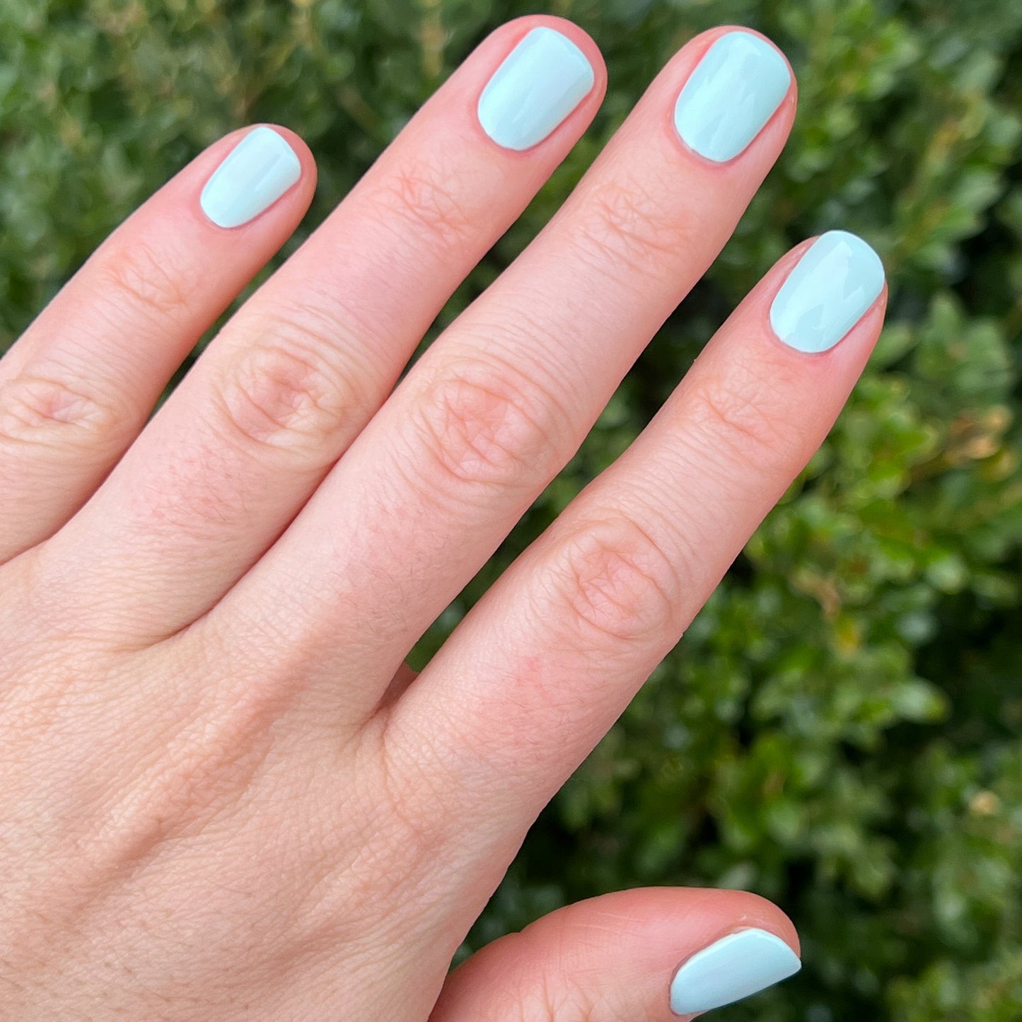 Hand with nails polished in pastel mint green Sleeping Bag gel polish by Olive and June outdoors