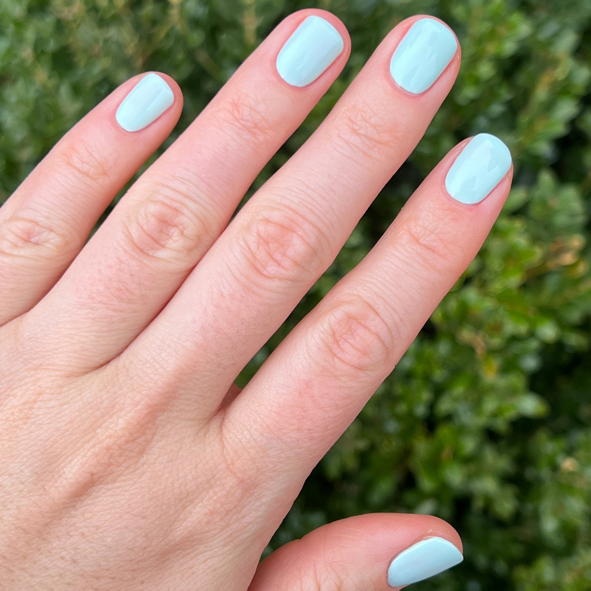 Hand with nails polished in pastel mint green Sleeping Bag gel polish by Olive and June outdoors