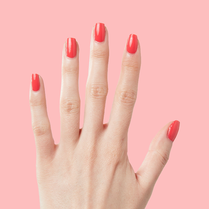 Hand with long nails painted in Field Day juicy watermelon red polish for a bright at home manicure look