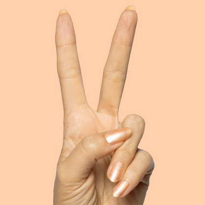 Hand with natural nails painted in Sunlit warm golden peach shimmer gel polish showing peace sign on peach background