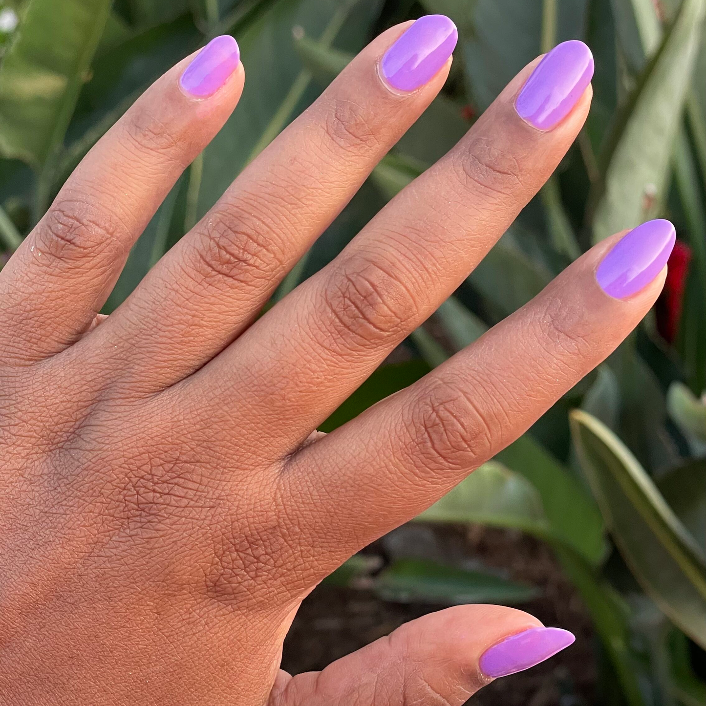 Hand with smooth nails painted bright purple Tennis Skirt polish for a glossy, quick-dry at-home manicure look
