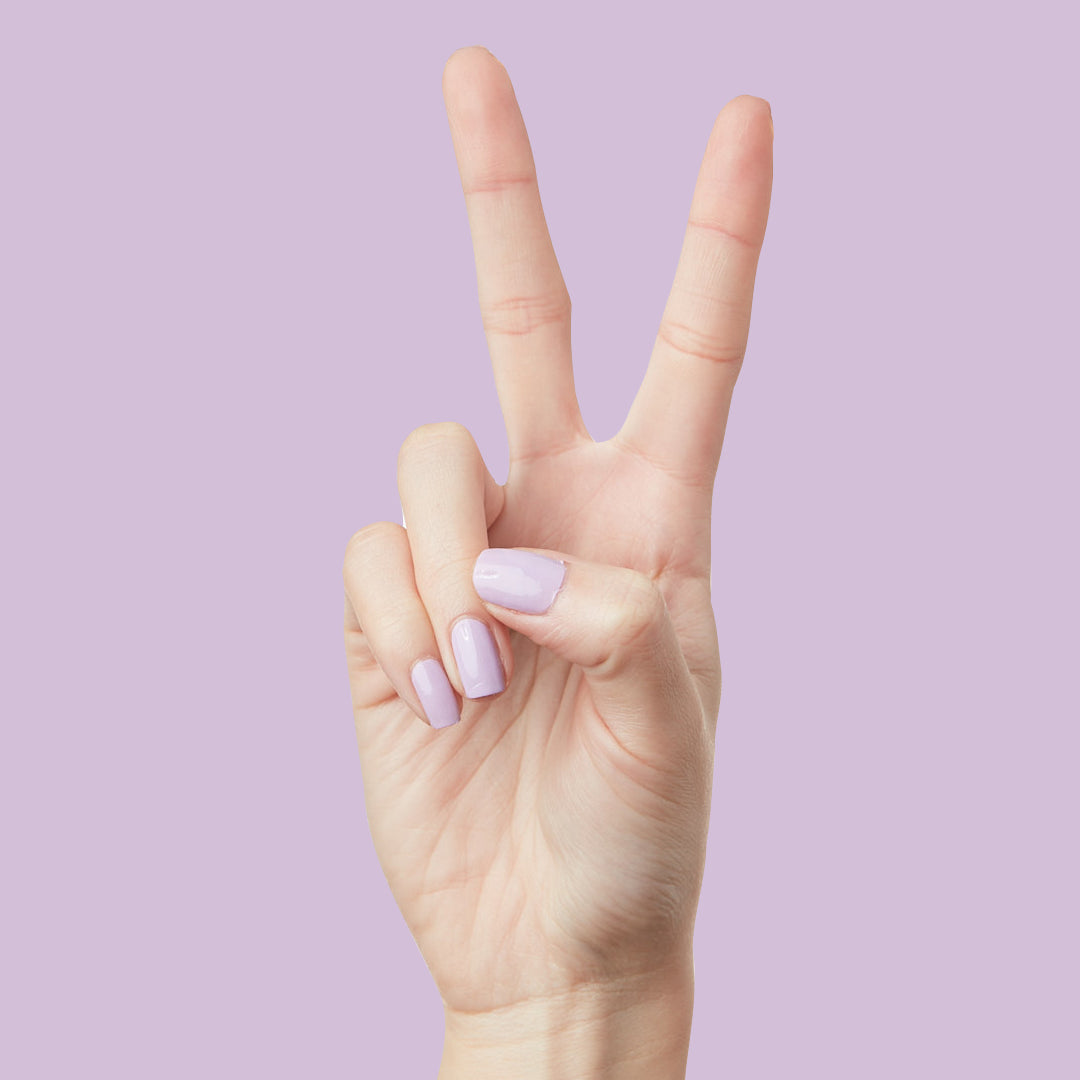 Hand showing peace sign with nails painted in You're Invited lilac gel polish for a long-lasting mani by Olive and June