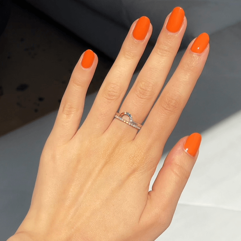 Hand with nails painted in vibrant tangerine shade "You're a 10" gel polish showcasing a fresh and smooth manicure