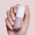 Hand holding Baroque quick dry gel polish bottle with pearly iridescent finish on natural short nails