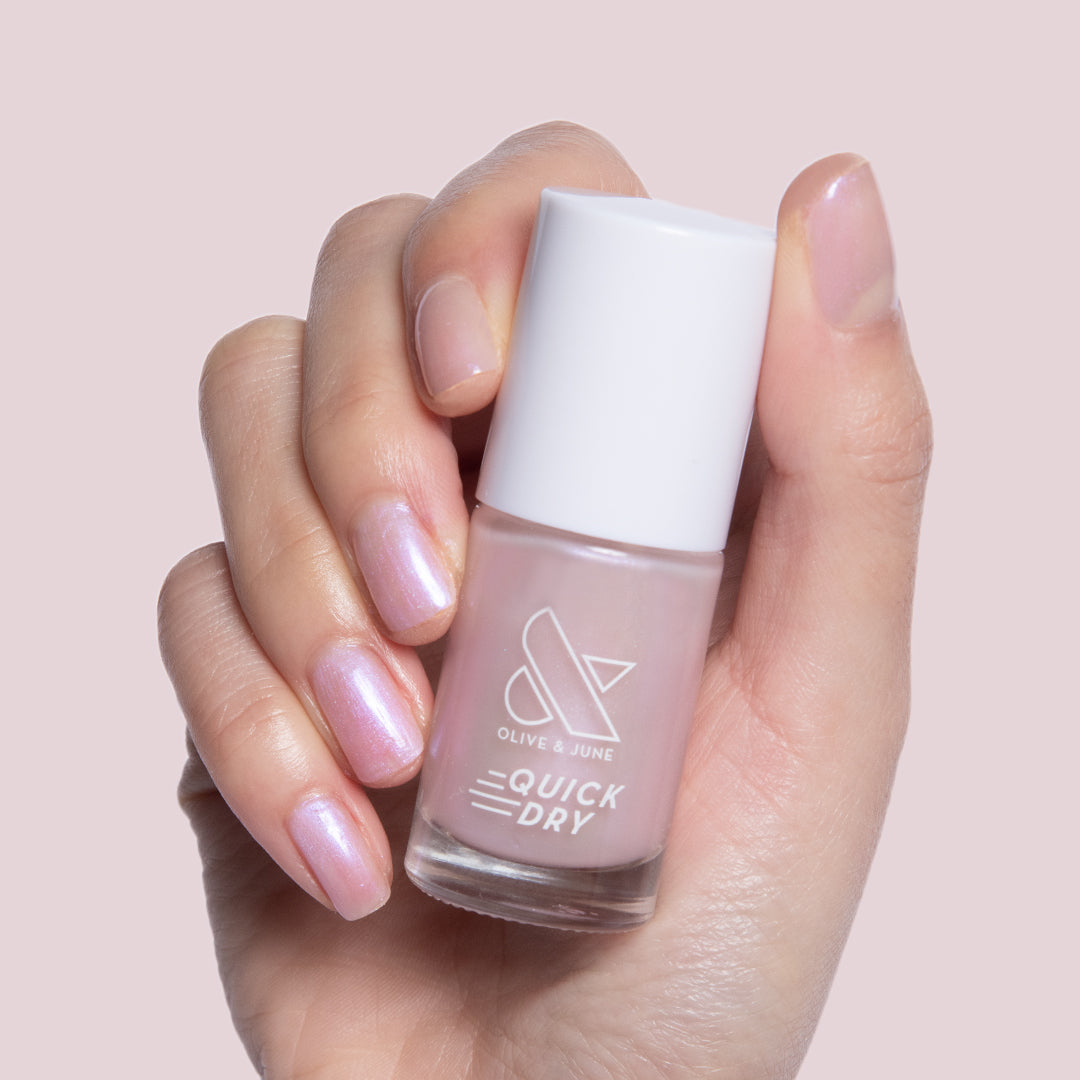 Hand holding Baroque quick dry gel polish bottle with pearly iridescent finish on natural short nails