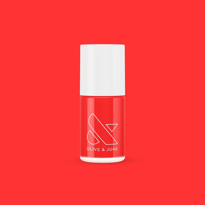 Lava nail polish bottle in vibrant spicy orange red from Olive and June against solid red background