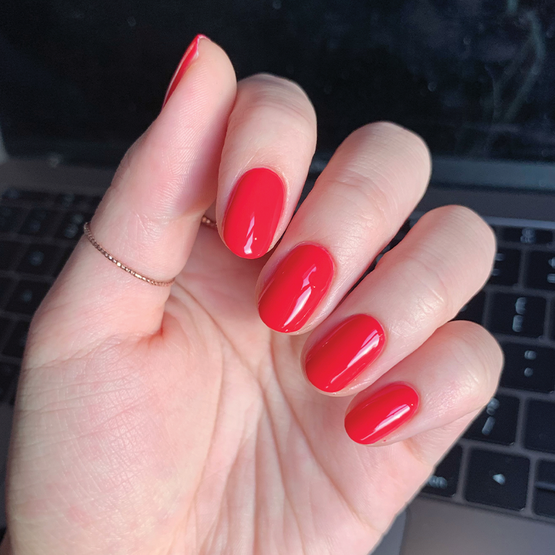 Hand with nails painted in glossy Hibiscus nail polish showing a smooth, bright tropical pink manicure at home