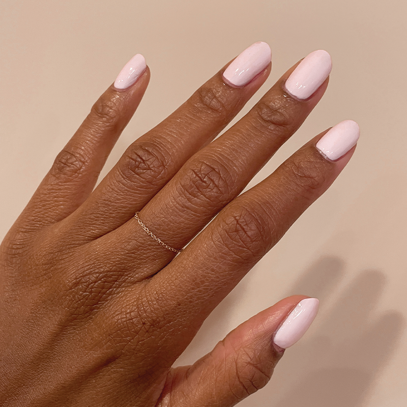 Hand with medium-length nails coated in glossy PINK SANDS polish for a radiant at-home manicure look