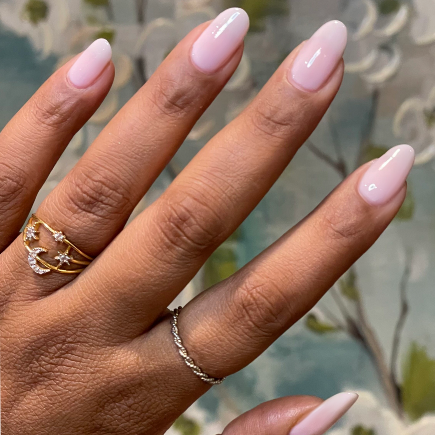 Hand with glossy almond-shaped nails painted in sheer milky pink Puffball gel polish manicure
