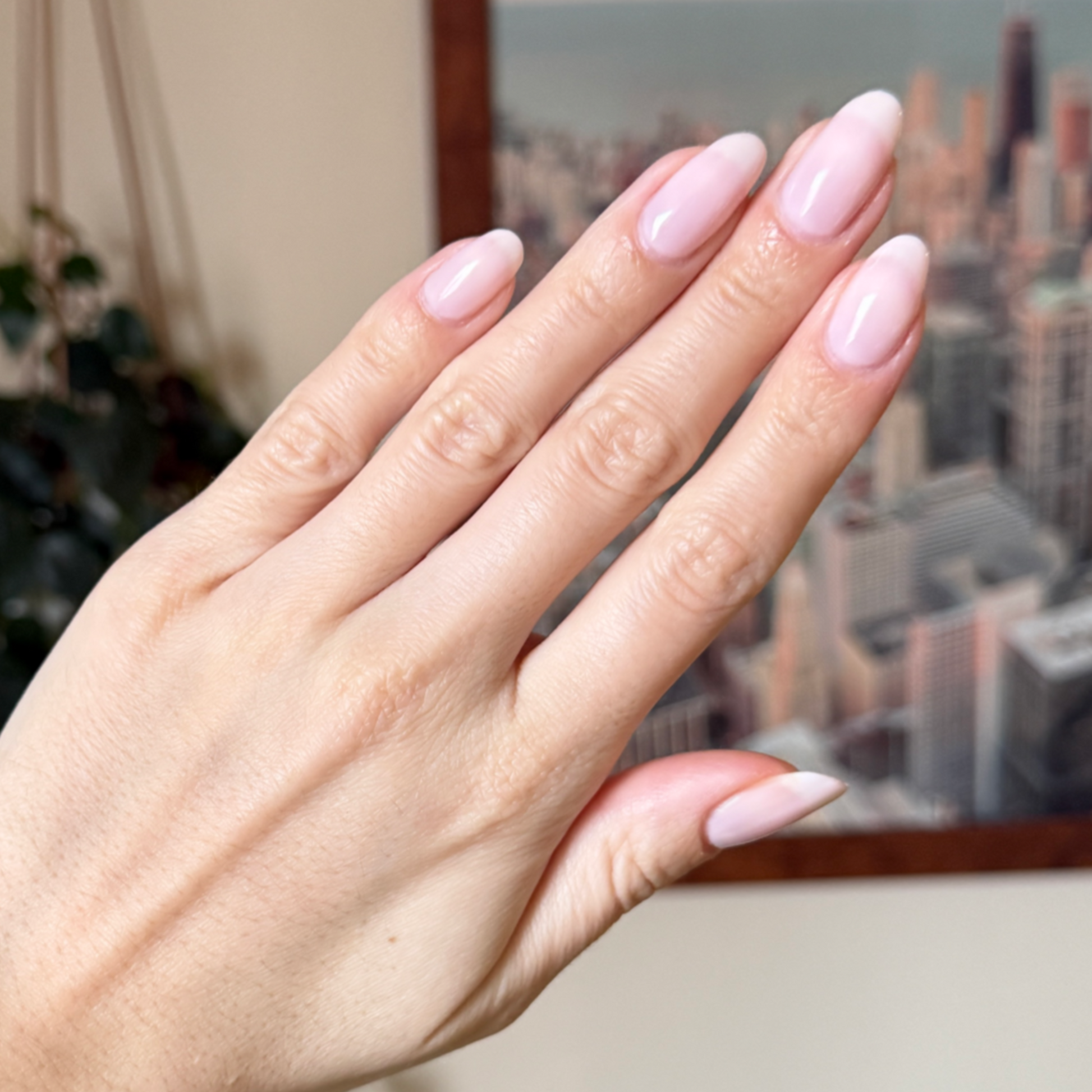 Hand with long almond-shaped nails polished in sheer milky pink Puffball gel polish manicure