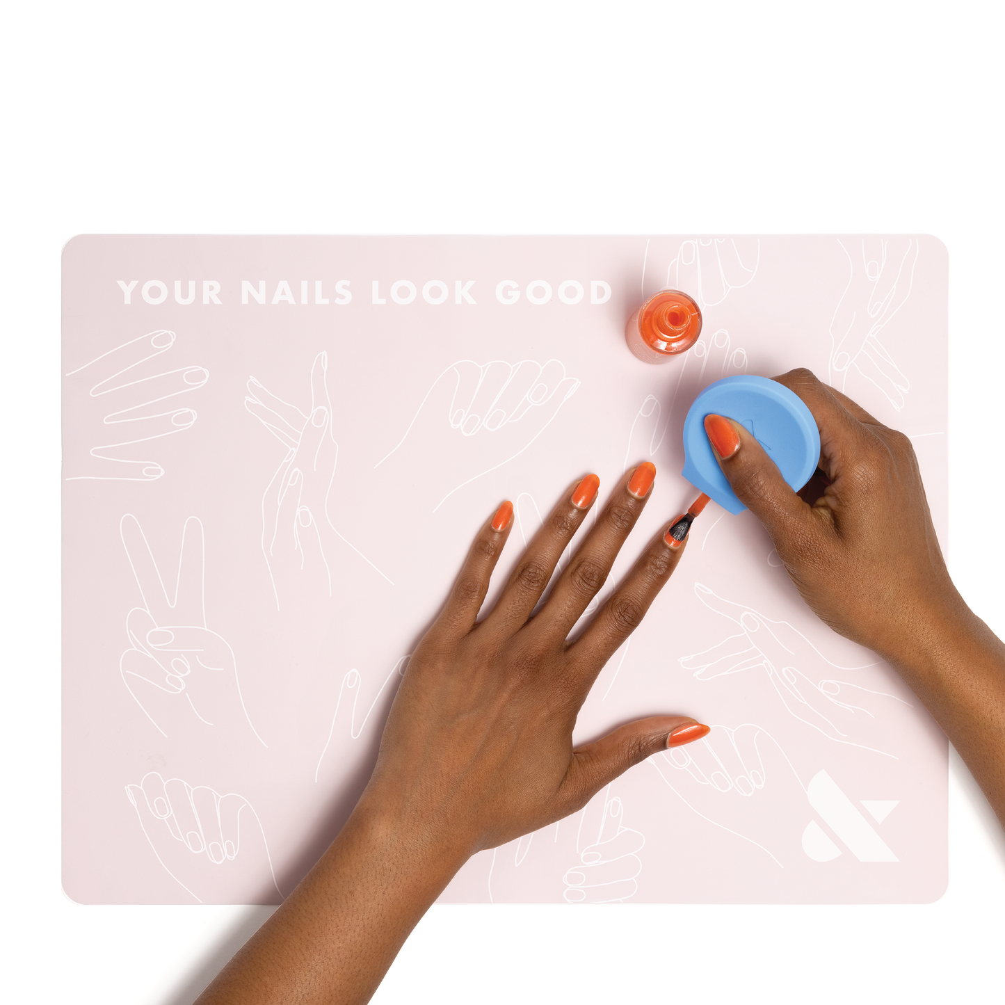 Silicone Painting Mat in soft pink with hand illustrations and person applying orange polish during at home manicure session